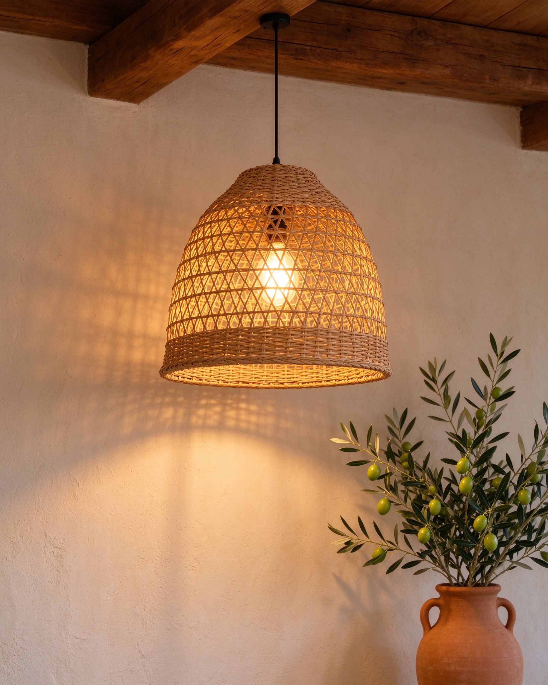 Handwoven rattan pendant lamp glowing over plaster wall